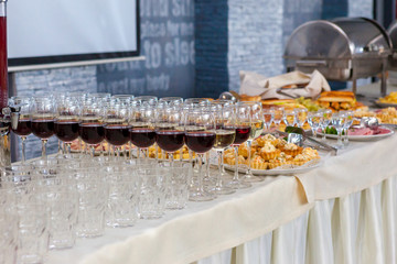 Alcoholic beverages in glasses and snacks on buffet table, catering