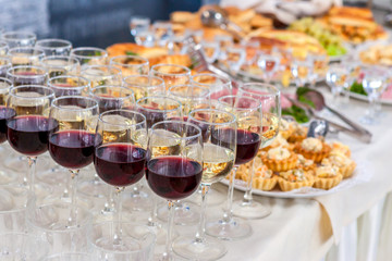 Alcoholic beverages in glasses and snacks on buffet table, catering
