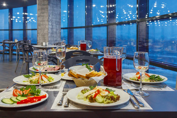 Served on a Banquet at restaurant table with dishes, snacks, Cutlery, and wine glasses. The European food.