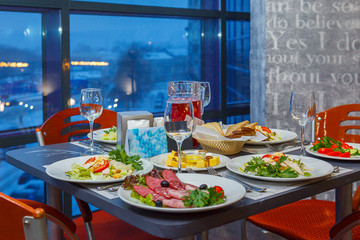 Served on a Banquet at restaurant table with dishes, snacks, Cutlery, and wine glasses. The European food.