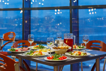 Served on a Banquet at restaurant table with dishes, snacks, Cutlery, and wine glasses. The European food.