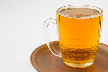 Glass mug with beer on  ceramic plate. White background