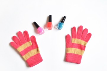 Nail polish and winter gloves/ Bottles with pink, red and blue nail polish with sparkles and female pink gloves. Photo for beauty blog, cosmetic sites. Online shopping concept