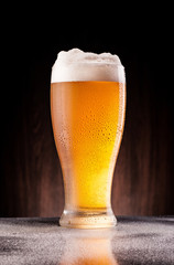 light beer in frosty glass over dark wooden background