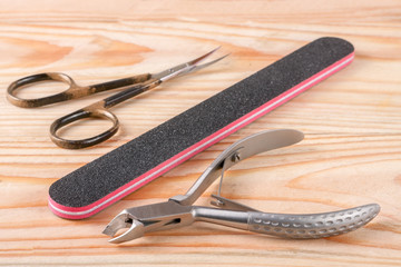 nail scissors file and clippers to remove the cuticle care products on a light wooden background