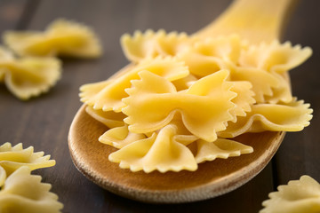 Raw farfalle or bow-tie pasta on wooden spoon, photographed with natural light (Selective Focus,...