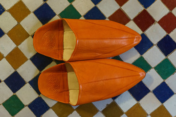 Traditional orange slippers in vintage Morocco background