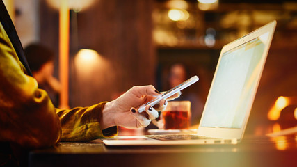 Photo with a focus on female hands typing e-mail on a smartphone. A freelancer girl is working in a...