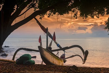 Poster Balinese Traditional Outrigger Fishing Boat. A Balinese fishing boat, called a jukung, on the beach in the Amed area of eastern Bali during a glorious sunrise. © LoweStock