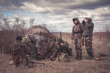 Store enrouleur tamisant Chasser Chasseurs se préparant à la chasse en équipe dans un domaine rural avec tente de chasse par temps couvert