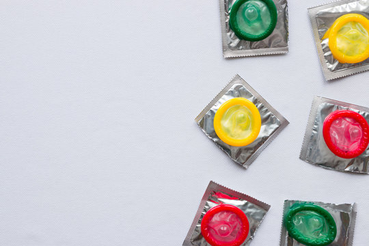 Open colored condoms on a white background