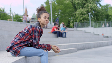 Beautiful young african american woman relaxing in urban background.