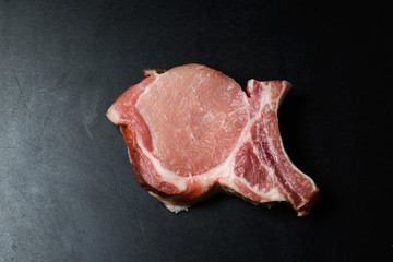 Top view raw pork chop steak and garlic, pepper, salt on wooden background.