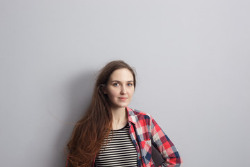 Fototapeta premium Girl in a red plaid shirt standing near the wall and looking confidently forward