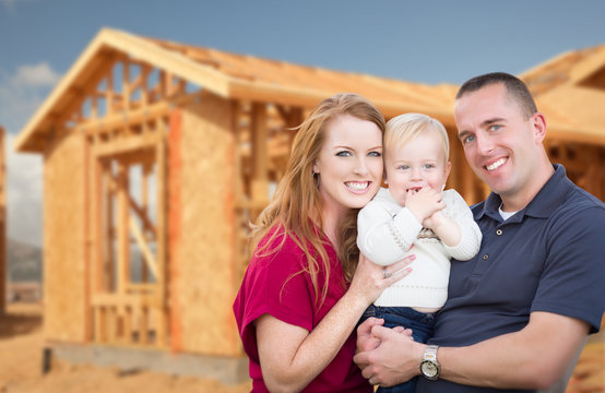 Happy Young Military Family Outside Their New Home Framing at the Construction Site.