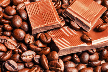 Broken chocolate bar and spices on wooden table.