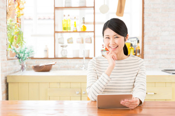 young asian woman using tablet in the dining