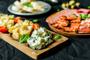 Close up of Italian cold meat and cheese antipasti delicatessen platter against black background. Selective focus
