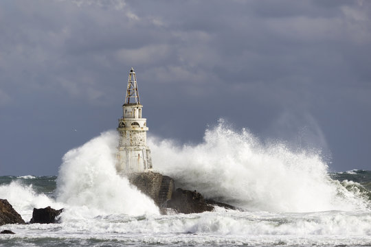 Lighthouse over waves in a stormy sea in the sunlight