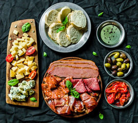 Flat lay of Italian cold meat and cheese antipasti delicatessen platter against black background