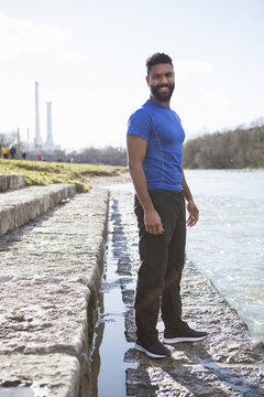 Athletic man with beard standing by the riverside