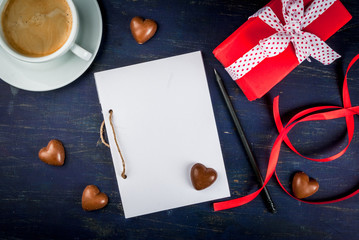 Preparations for Valentine's Day: a notebook for congratulation or sweet notes, gift, candy in the form of hearts, top view, copy space