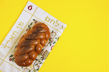Shabbat shalom, challah on a napkin and yellow background. Not isolated, copy space, author's processing.
