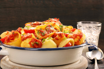 Lumaconi pasta with tomato sauce on wooden background