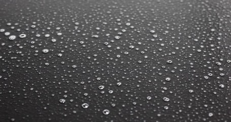 Spraying a black dusty surface with cleaner then wiping it clean with a white paper towel.