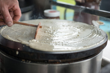 Spreading Crepe Batter on Skillet with Wooden Trowel