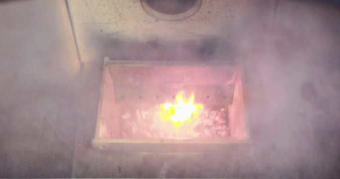 Video of the combustion chamber of a pellet stove smoking with ignition then lighting the pellets.