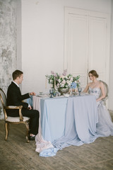 The newly-married couple sitting at the wedding centerpieces. Bridal fashion.