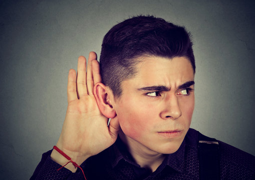 Curious worried man with hand to ear listening to gossip