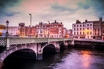 Naklejka premium Historyczny most Grattan nad rzeką Liffey w Dublinie w Irlandii o zachodzie słońca