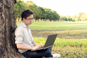 man is using computer laptop for working at outdoor in public park.