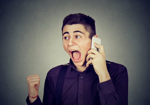 angry young man screaming on mobile phone