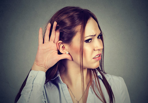 Curious worried woman with hand to ear listening to gossip