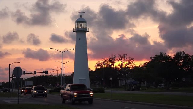 Lighthouse at sunset as cars drive past in Biloxi, Mississippi