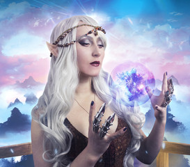 Elf girl photo. Beautiful elf girl holding a magic ball on fantasy background photo.