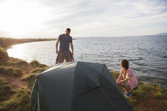 Young couple building up tent on water's edge