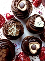 Chocolate cupcakes with  heart shaped
candies on a festive Valentine's day themed background