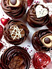 Chocolate cupcakes with  heart shaped
candies on a festive Valentine's day themed background
