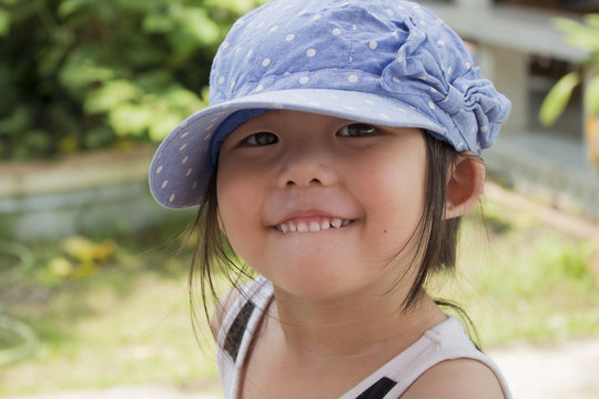 Little cute girl wearing a cap in garden. Smiling child