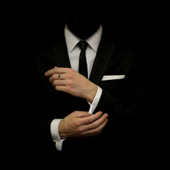 Man in a black suit and white shirt and black tie on a black background. Without a face. The...