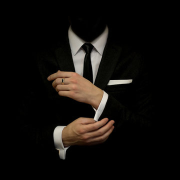Man in a black suit and white shirt and black tie on a black background. Without a face. The businessman in the dark. Studio shot