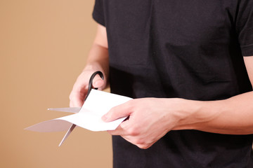 Man hand cut white paper with scissors.