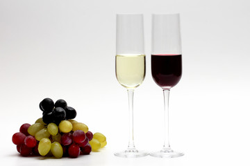 two glasses with red and white wine with grapes on a light backg