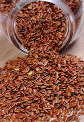 Linseed spilling out of jar on wooden background