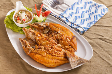 A dish of crispy Thai style deep fried whole sea bass fish served with spicy mango sauce. © akeeris