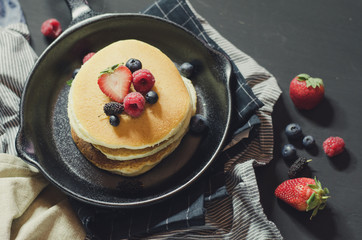 Home made pancakes with berries on metal frying pan decorated wi